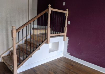 Staircase and landing with cubby and heat vent grate cover in room with dark hardwood floors