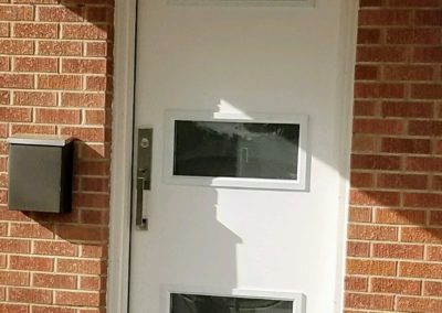 New front door with 3 clear glass windows at brick home