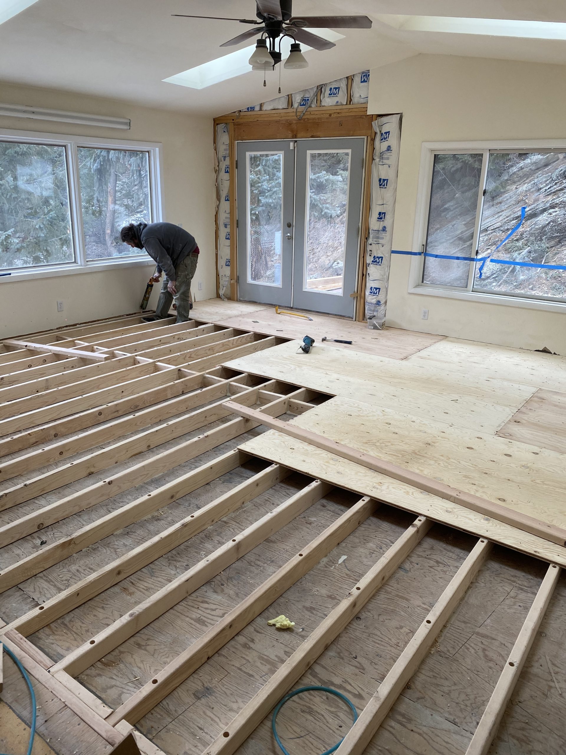 Builder hammers plywood subflooring on top of leveled 2x4s