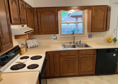 The kitchen was in good shape but very dated with oak cabinets, formica countertops, electric range, and decorative trim above the sink.