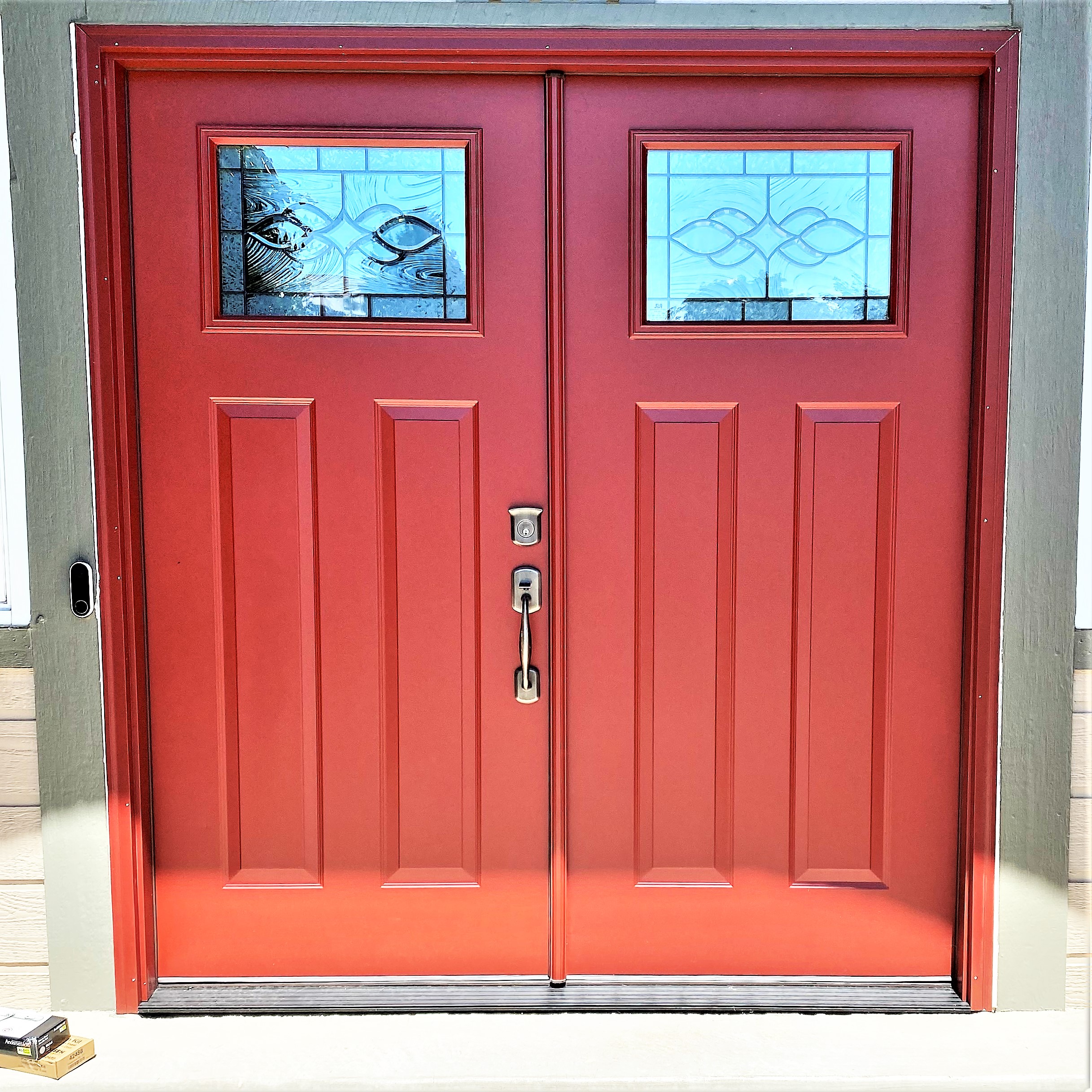 Red French entry doors, each with 2 vertical panels & a rectangular 1/4 lite, leaded glass window on top