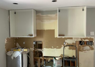 New modern white cabinetry being hung during home kitchen renovation