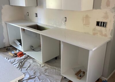 16. Modern white cabinets and solid stone countertops are installed in home kitchen renovation