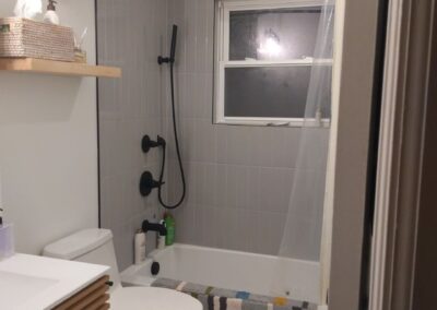 27. After home bathroom remodel, new stacked subway tile enclosure, floating shelves, tile flooring, and modern vanity.