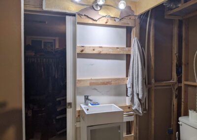 Existing basement bathroom with sink and lights on unfinished walls