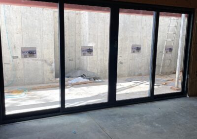 Interior view of installed black-framed oversized sliding glass doors offering floor-to-ceiling light and outdoor access in a new basement walkout.