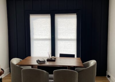 Dining room with custom board and batten paneling painted in Sherwin Williams Greenblack, featuring modern furnishings and a clean aesthetic.