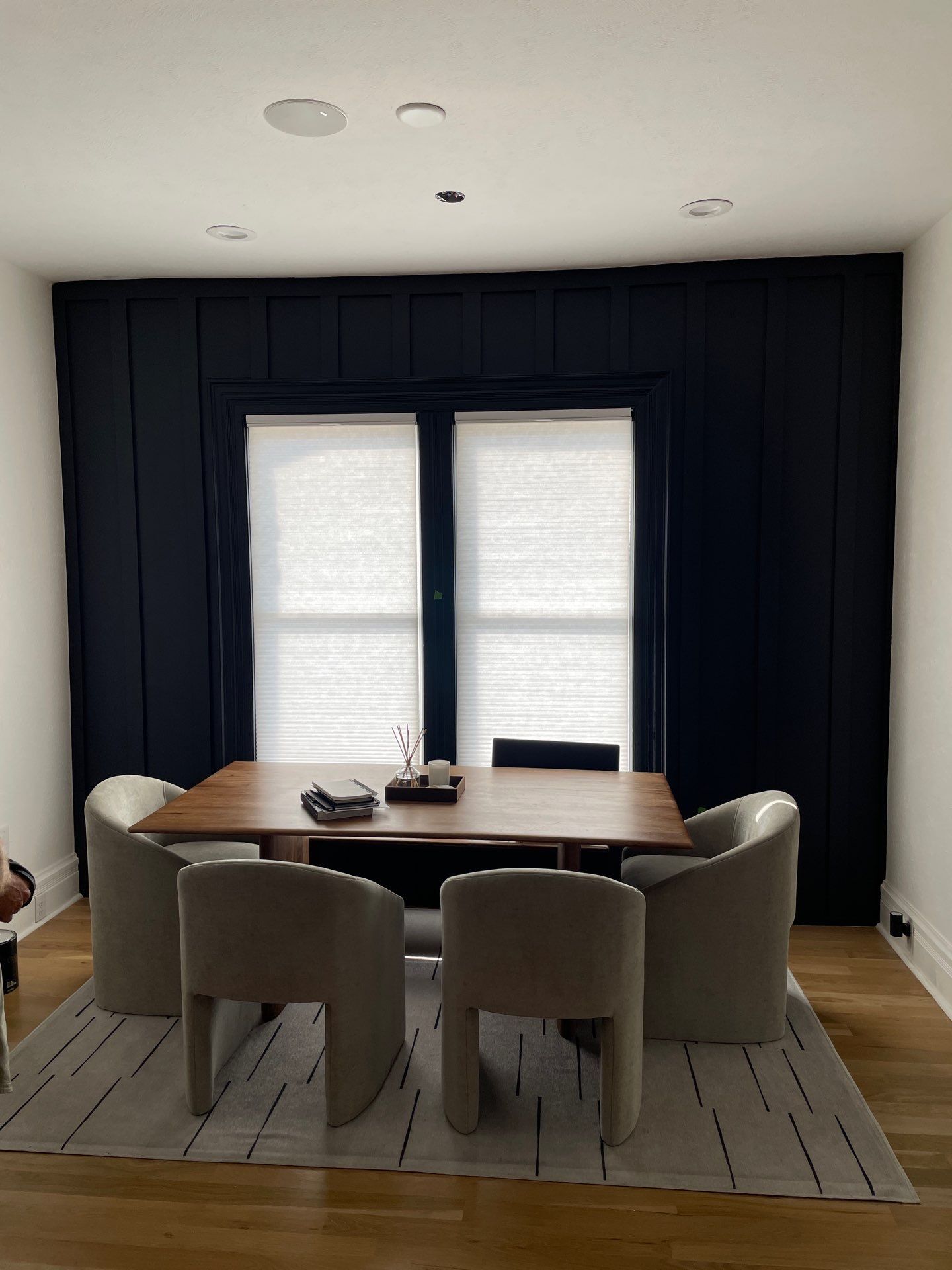 Dining room with custom board and batten paneling painted in Sherwin Williams Greenblack, featuring modern furnishings and a clean aesthetic.