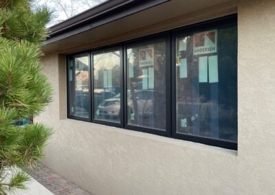 Exterior of home showing new black-framed oversized Andersen windows with multiple panes in a stucco wall