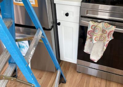 Close-up of white cabinet drawer fit precisely between refrigerator and stove in renovated kitchen.