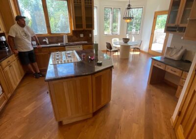 View of the existing kitchen with wood cabinetry, granite countertops, and outdated lighting layout before the renovation begins.