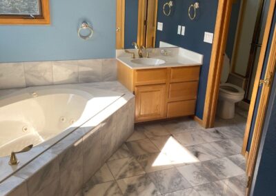 View of the existing primary bathroom featuring a built-in jetted tub with tile surround and a blue painted wall.