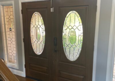 Interior view of traditional double entry doors with oval leaded glass, framed by matching decorative windows.