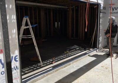 Framed rough opening for oversized sliding glass door in new construction, with Tyvek HomeWrap and exposed studs.