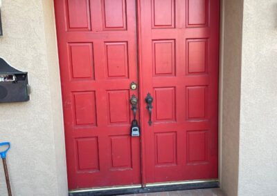 Exterior view of old red double French doors with outdated hardware and frame