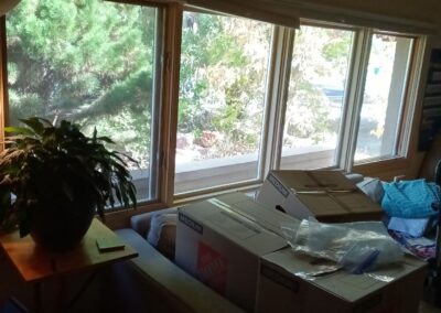Interior view of sunroom with old wooden windows partially covered by moving boxes