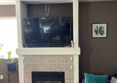 Original fireplace with square beige tile, a bulky surround, and a recessed TV nook with textured white columns.