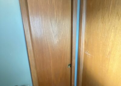 Two brown flush pocket doors in a bathroom with teal blue walls and tile flooring.