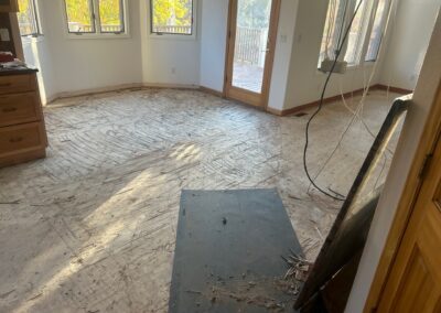 kitchen cleared of old flooring with subfloor exposed and wiring visible during remodel prep.