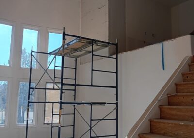 Scaffolding set up next to a partially drywalled loft wall during a home interior remodel.