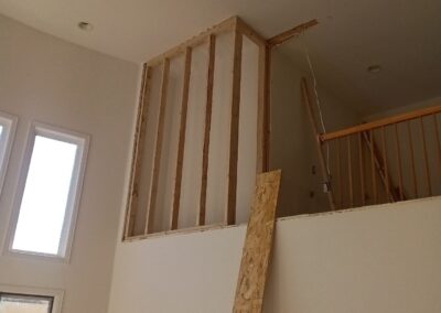 Framing a new loft wall during a home renovation, with exposed wooden studs visible above a white painted wall.