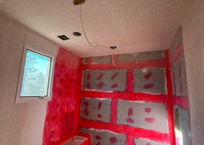 Walk-in shower area coated in red waterproofing membrane with built-in bench and recessed shelf.