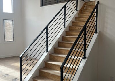 Modern black horizontal metal stair railing installed on staircase in remodeled home.