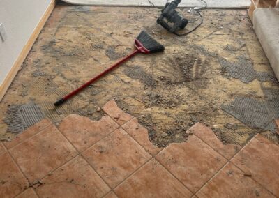 Floor demolition in progress with tile partially removed and exposed subfloor.