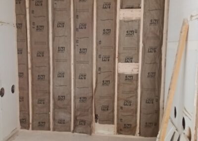 Wall insulation installed between exposed framing in room under construction.