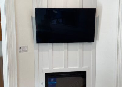 Board and batten paneling in progress surrounding a mounted TV and new electric fireplace unit.
