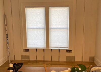 Board and batten paneling installation in progress beneath a large window in the dining room.