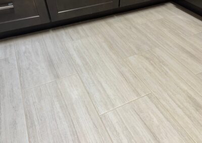 Close-up of newly installed light gray tile flooring with a textured finish.