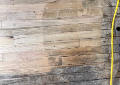 Side-by-side view of old, worn hardwood flooring and newly sanded planks during floor restoration process.