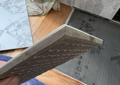 Close-up of marble tile with an angled cut, prepared to fit snugly against hardwood flooring.