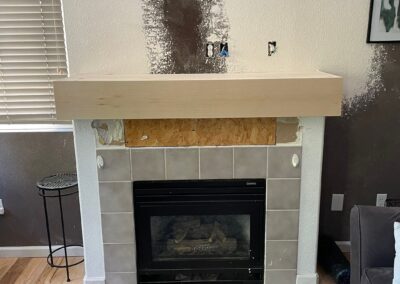 Fireplace during demolition with drywall removed and an unfinished wooden frame exposed around the opening.
