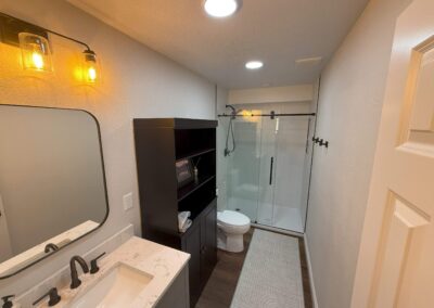 Finished basement bathroom with glass shower and storage cabinet