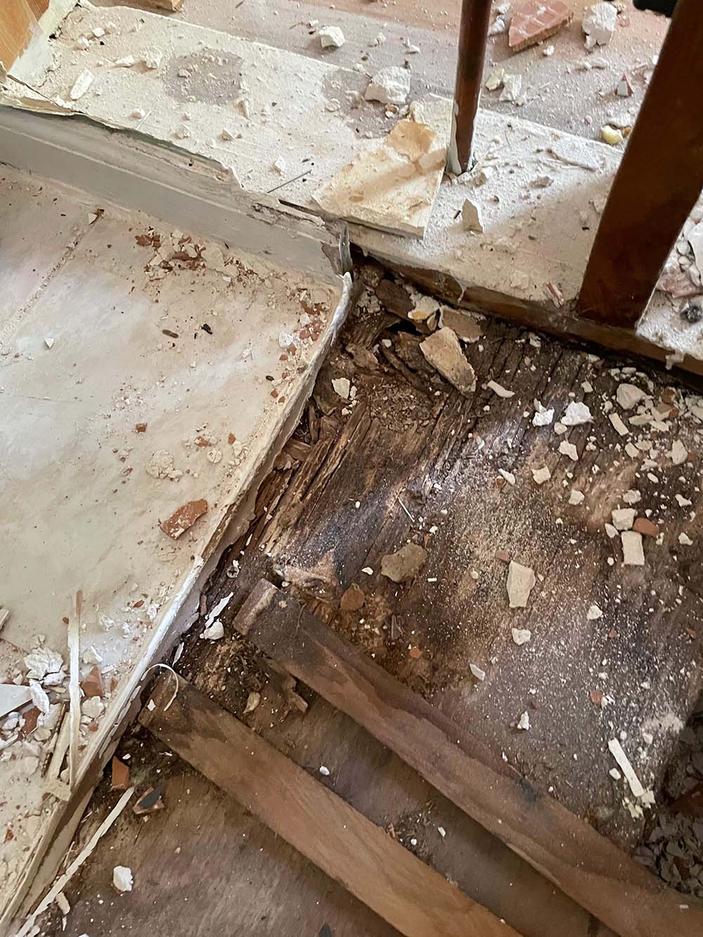 Two men in masks and red shoe covers inspect HVAC and plumbing systems in a utility room.