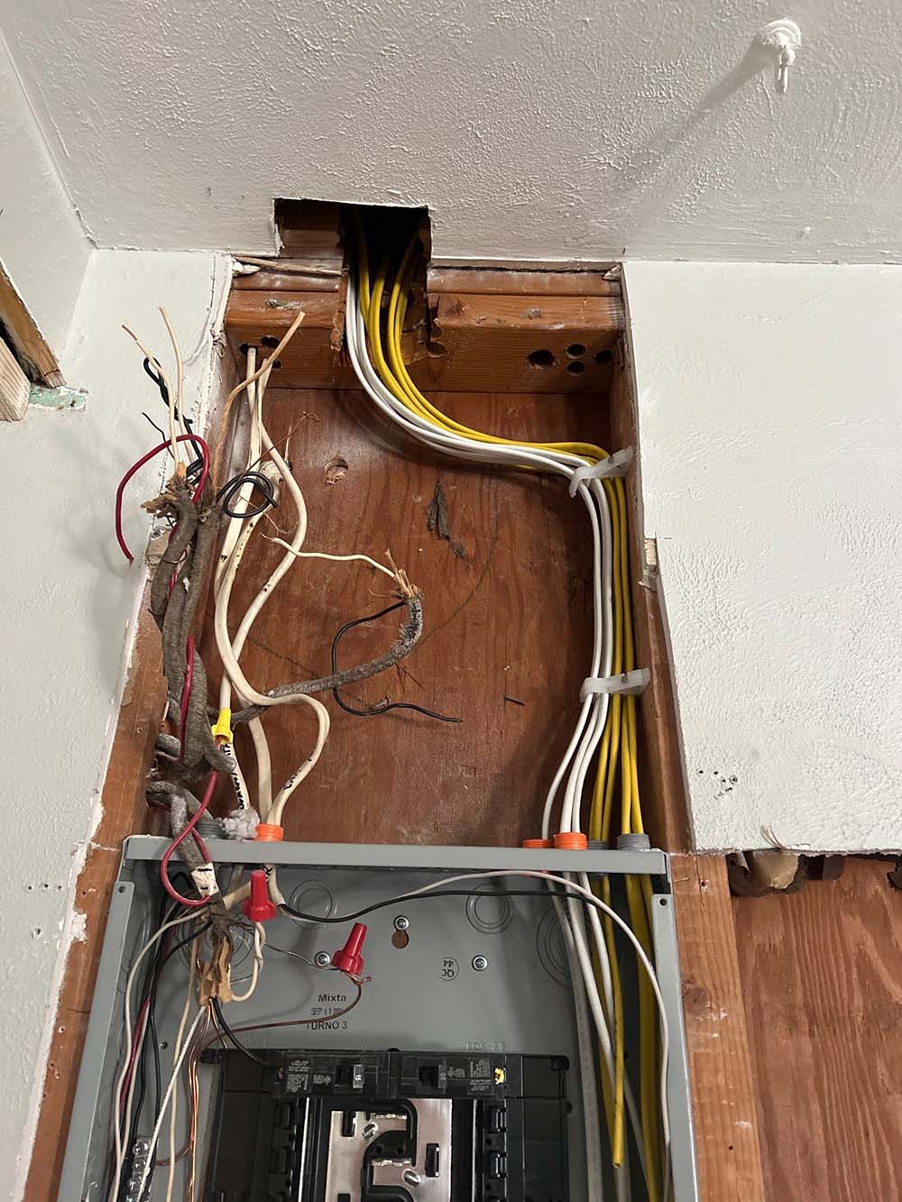 Two men in masks and red shoe covers inspect HVAC and plumbing systems in a utility room.