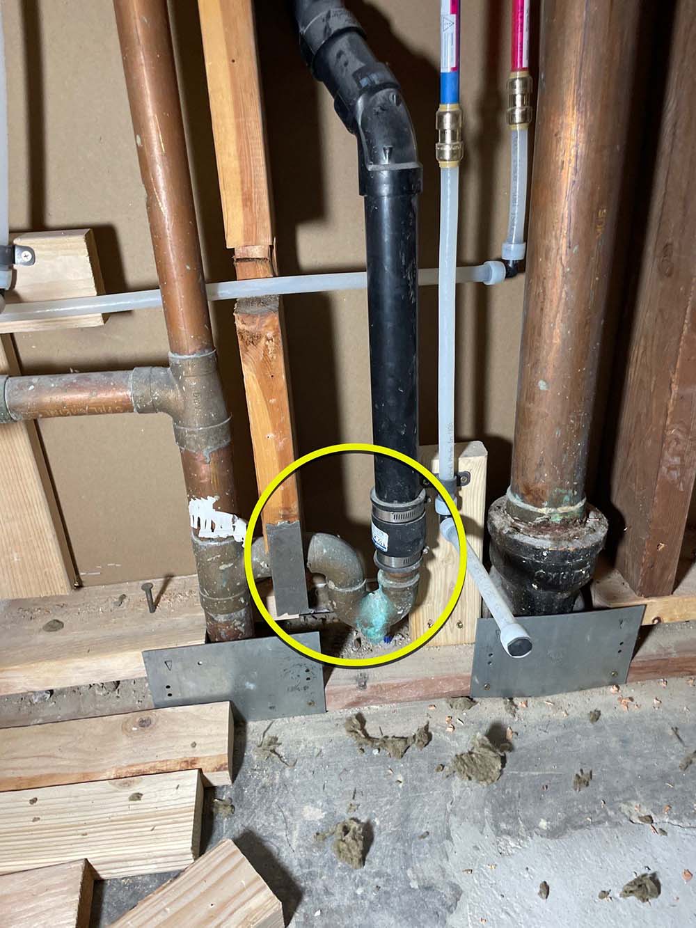 Two men in masks and red shoe covers inspect HVAC and plumbing systems in a utility room.