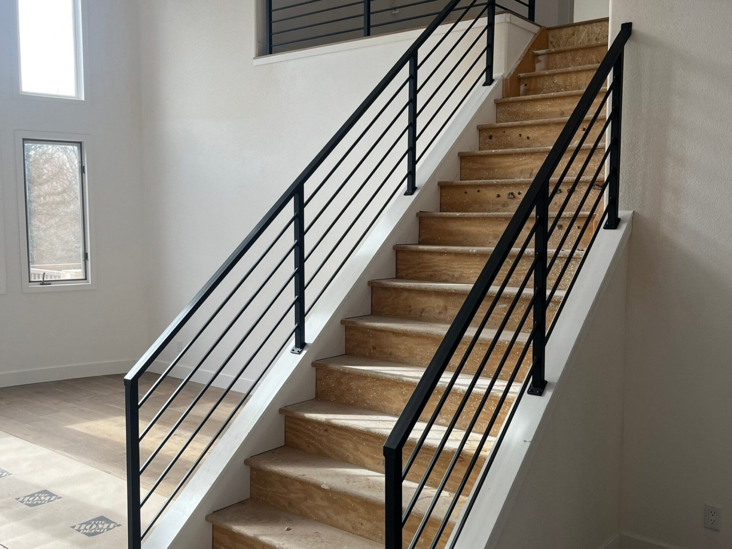 Modern black horizontal metal stair railing installed on staircase in remodeled home.